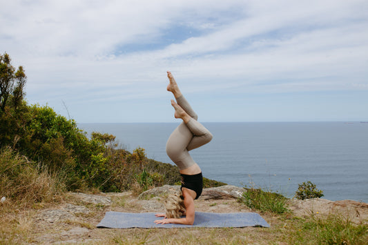 Yogi on top of cliff doing headstand on Second Earth Yoga Mat