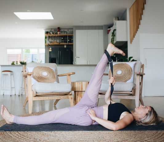 Yogi using yoga strap for deep hamstring stretch